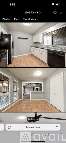 A kitchen with white cabinets and a black fridge.