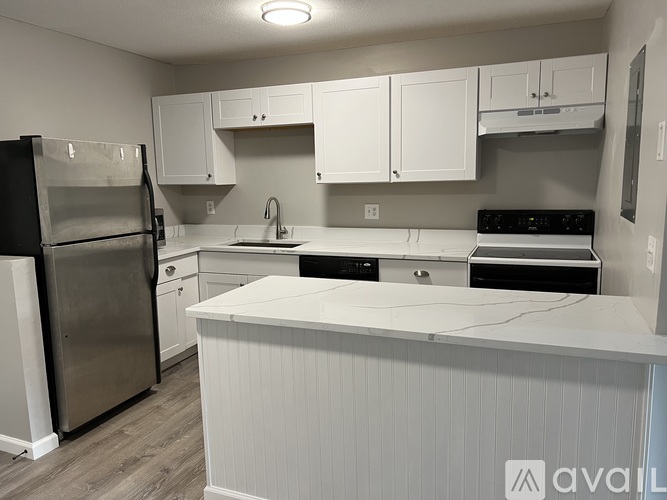 A kitchen with white cabinets and a black refrigerator.