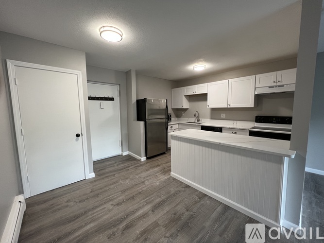 A kitchen with white cabinets and a wooden floor.