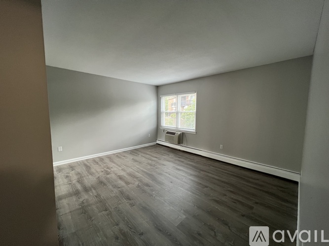 A room with wooden flooring and a window with a view of a building outside.