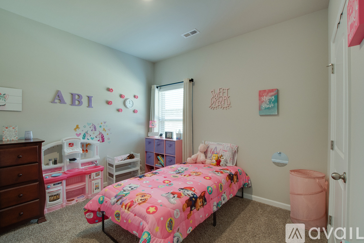 A bedroom with a pink bed and a dresser.