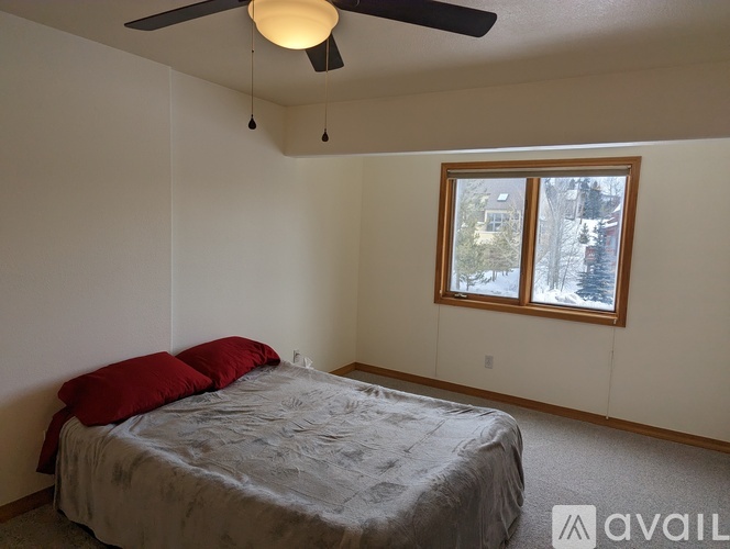 A bedroom with a bed, ceiling fan, and window.