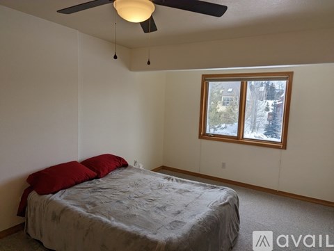 A bedroom with a bed, ceiling fan, and window.