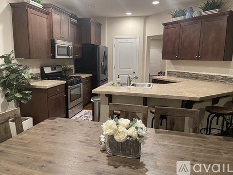 A kitchen with wooden cabinets and a wooden table with a vase of flowers on it.