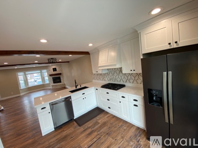A kitchen with white cabinets and a black refrigerator.