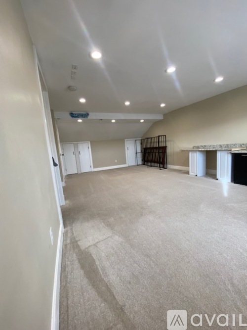 A spacious room with a carpeted floor and a ceiling with recessed lighting.