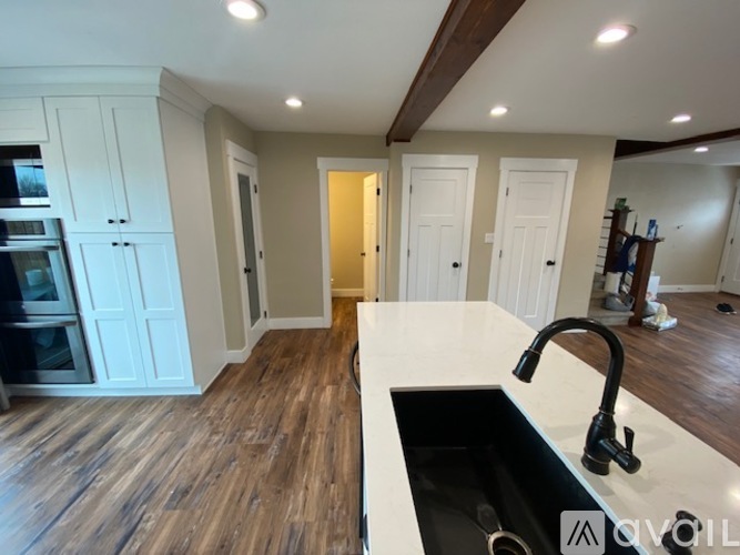 A kitchen with a black sink and wooden floors.