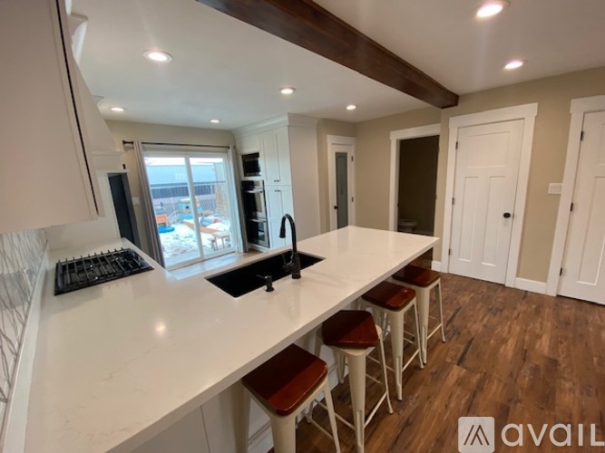 A kitchen with white countertops and a large island with bar stools.
