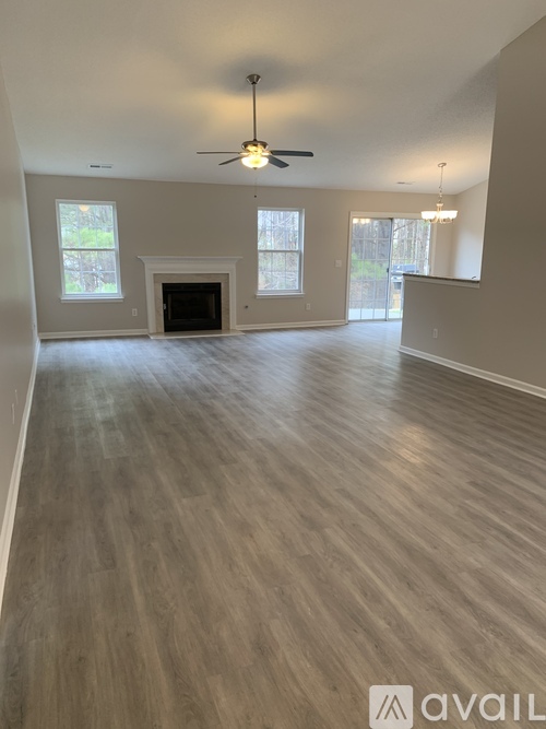 A spacious room with a fireplace and wood flooring.