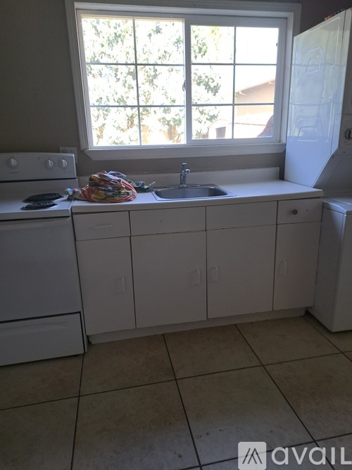 A kitchen with a stove, sink, and window.