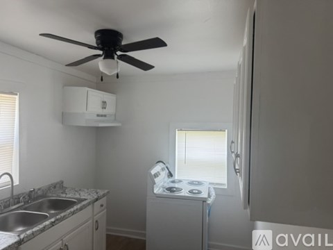 A kitchen with a fan, a washing machine, and a dishwasher.