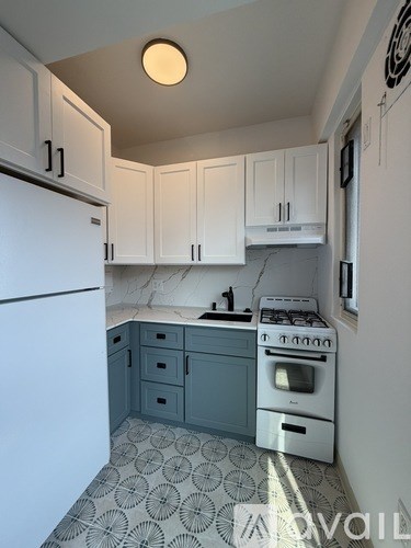 A kitchen with white cabinets and a white fridge.