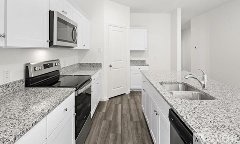 A kitchen with white cabinets and granite countertops.
