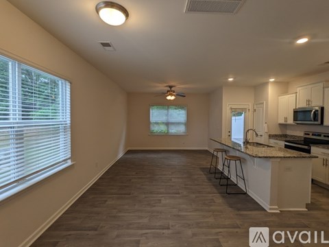 A kitchen area with a bar stool and a window with blinds.