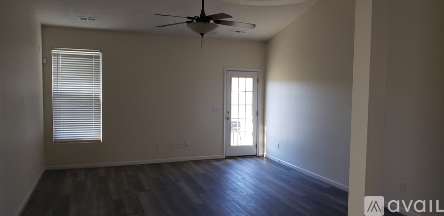 A room with a fan and a door leading to a sunny area.