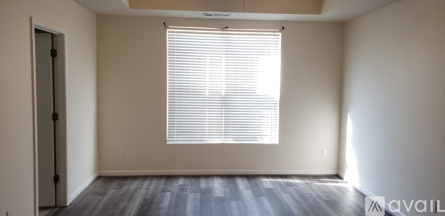 A room with a door, window, and wooden floor.