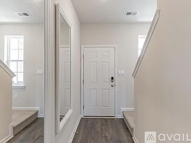 A hallway with a white door and a wooden floor.