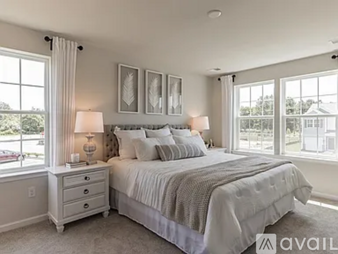 A bedroom with a large bed, two lamps, and pictures on the wall.