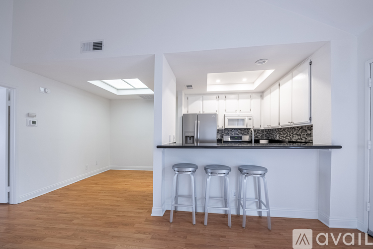 A kitchen with white cabinets and a bar area with stools.