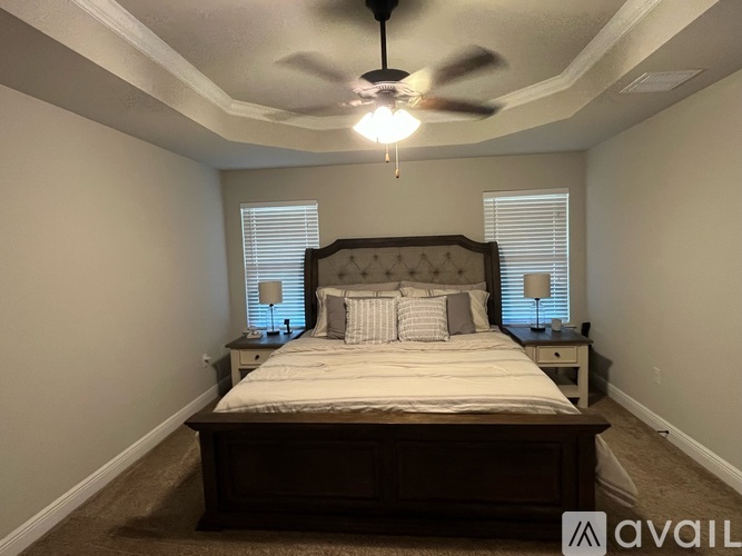 A bedroom with a large bed and a ceiling fan.