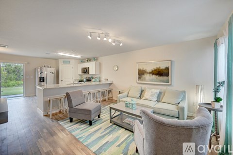 A living room with a grey sofa, a grey armchair, a wooden floor, and a painting on the wall.