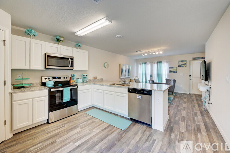 A kitchen with white cabinets and wooden floors.