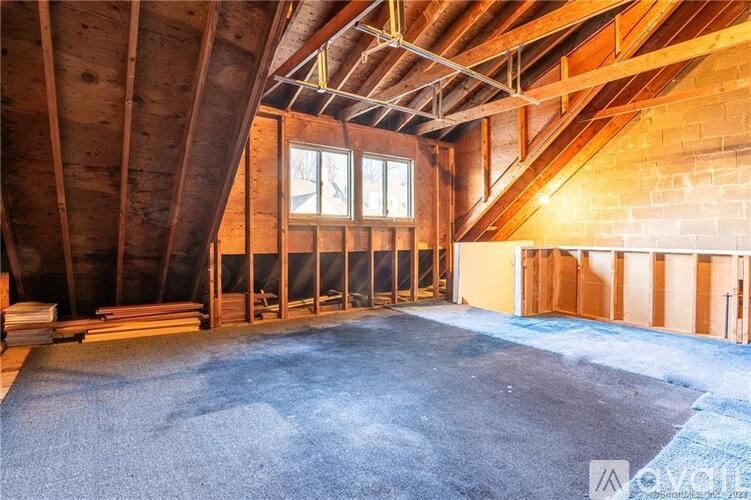 A spacious attic room with wooden beams and a concrete floor.