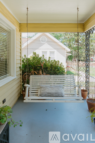 A porch with a swing and plants.