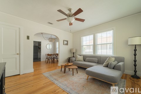 A living room with a grey couch and a fan.
