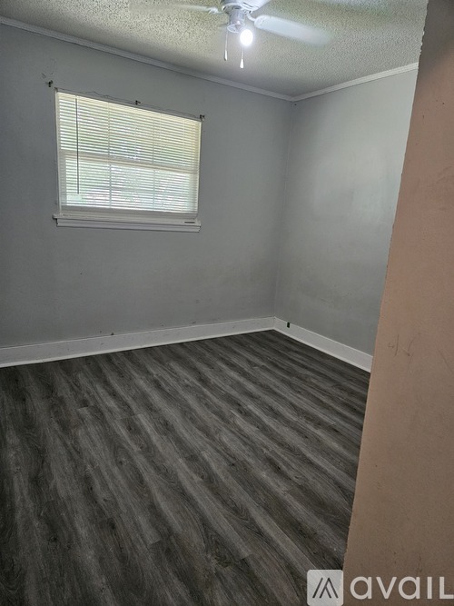 A room with a grey carpet and a window with blinds.