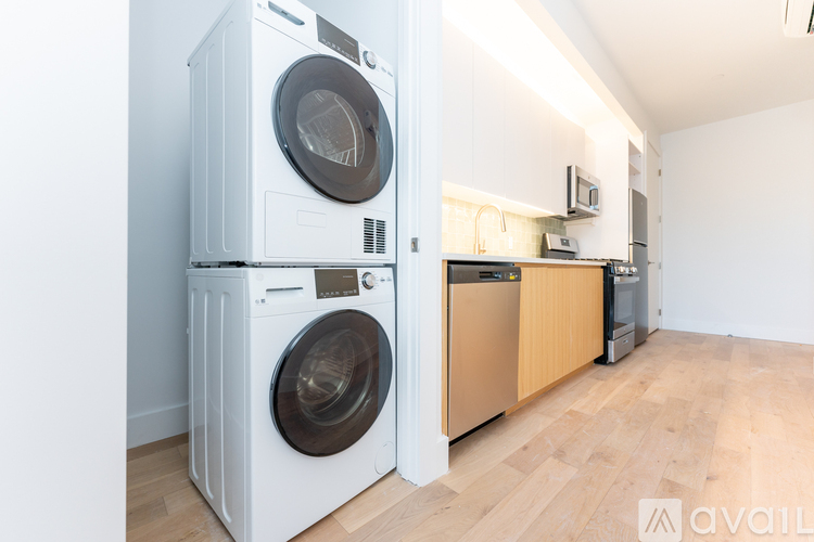 A white washing machine and dryer stacked on top of each other in a room with wooden flooring.