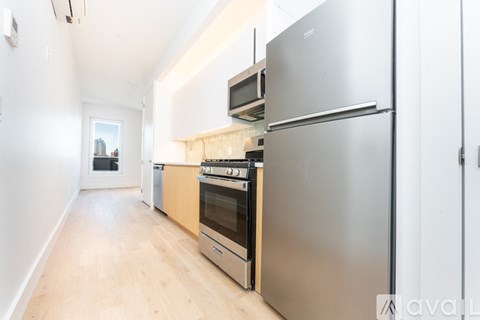 A kitchen with a stainless steel refrigerator and wooden cabinets.