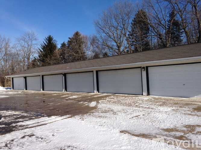 A row of garage doors are closed and the ground is covered in snow.