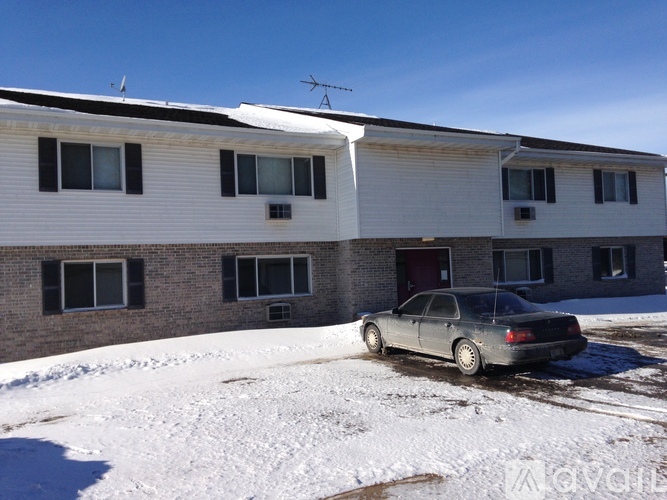 A car is parked in front of a building with a roof covered in snow.