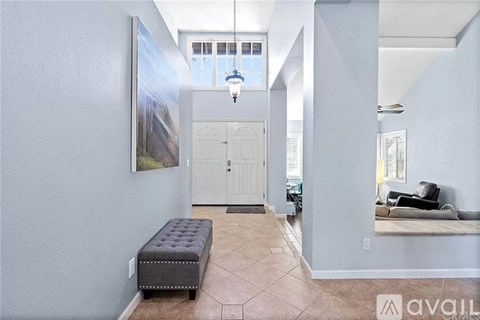 A living room with a grey bench and a painting on the wall.
