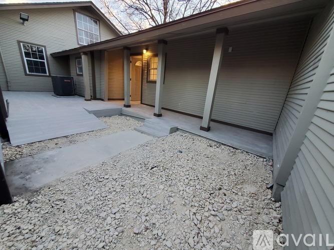 A house with a gravel driveway and a covered patio area.