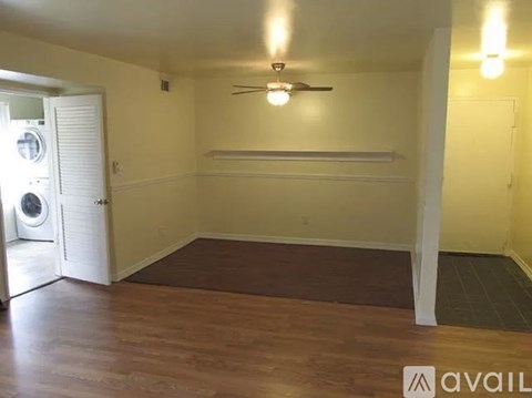 A room with a ceiling fan and a washing machine in the corner.