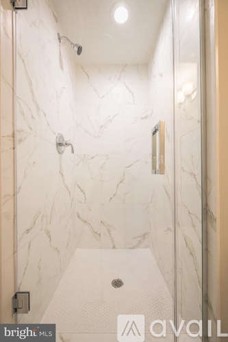 A white marble bathroom with a walk in shower.