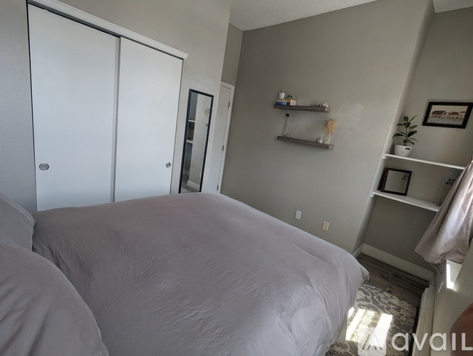 A bedroom with a bed, a closet, and a shelf with a plant on it.