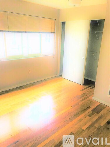 A room with wooden flooring and a window with blinds.