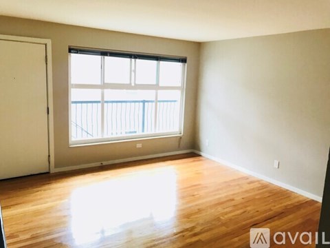 A room with wooden floors and a large window overlooking a balcony.
