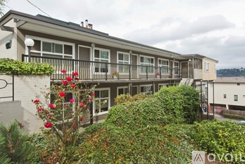 A building with a balcony and a garden in front.