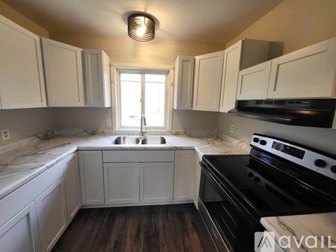 A kitchen with white cabinets and a black stove top oven.