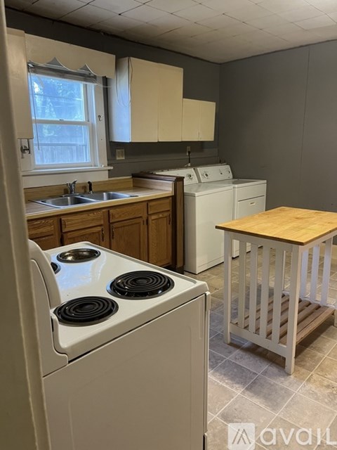 A kitchen with a white stove top oven and a wooden table.