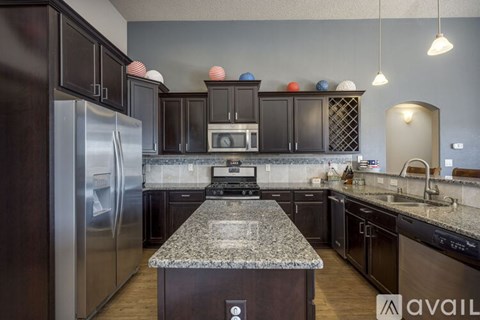 A kitchen with dark wood cabinets and granite countertops.