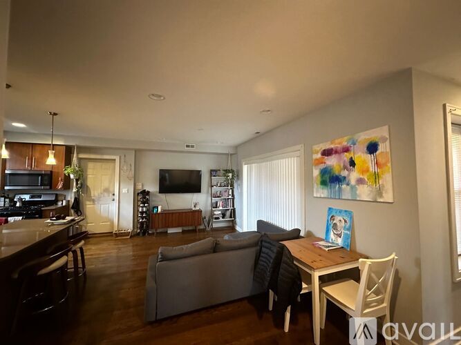 A living room with a grey couch and a painting on the wall.