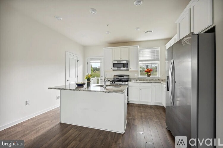 A modern kitchen with white cabinets and a stainless steel refrigerator.