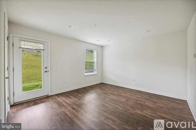 A room with wooden floors and a door leading to a grassy area.