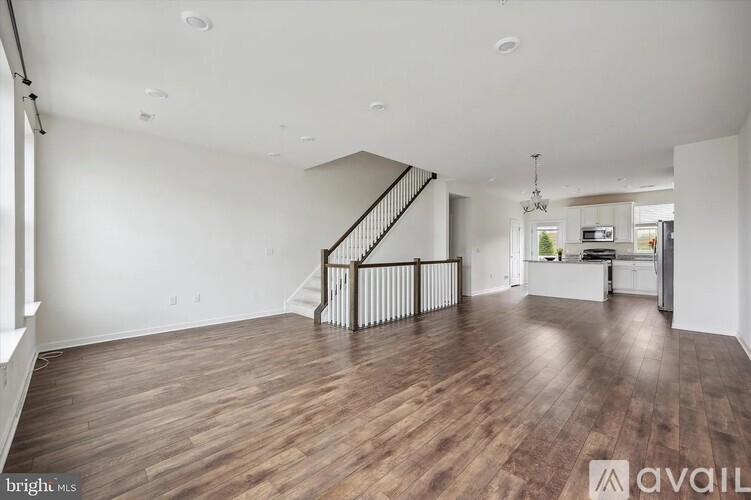 A spacious living room with wood flooring and a staircase with a metal railing.