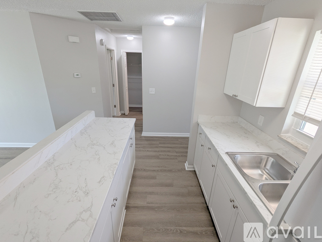 A kitchen with white cabinets and a marble countertop.